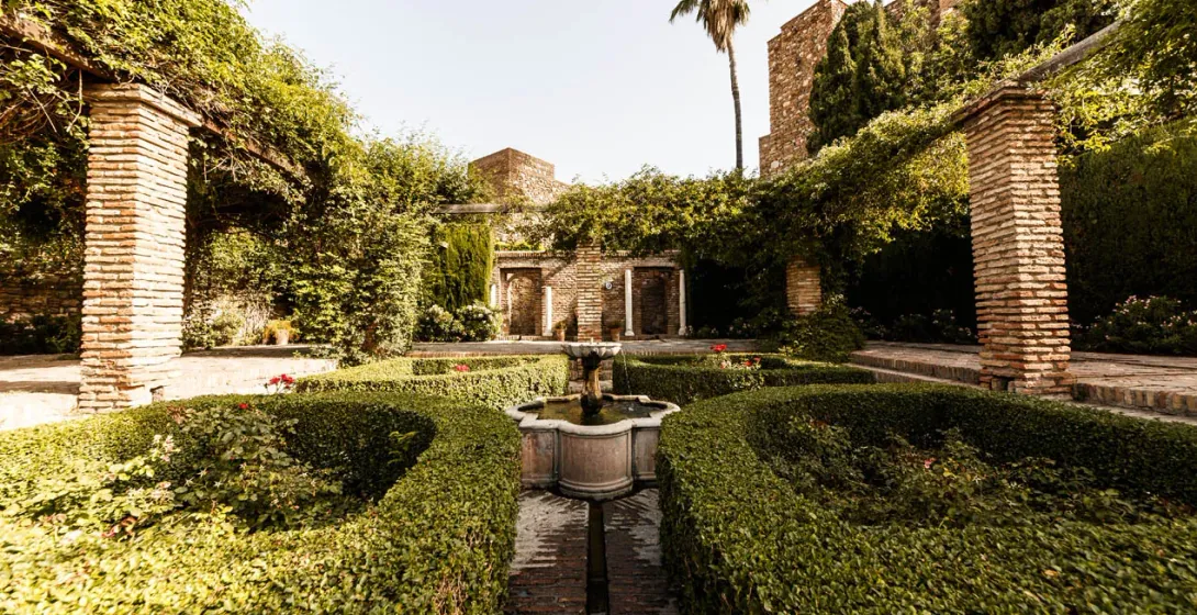Sereno patio en Sevilla, España, con una fuente y exuberante vegetación.