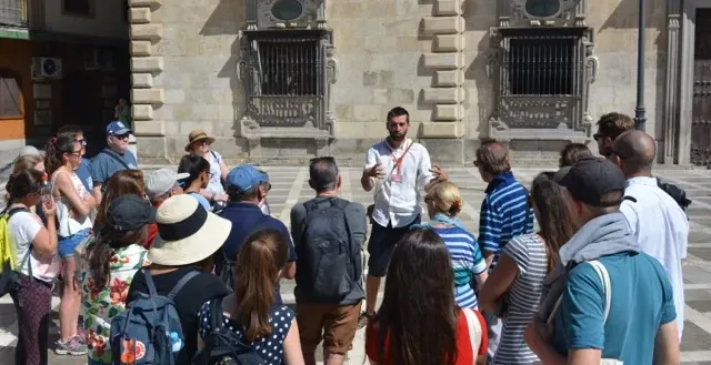 Un guía turístico conduce a un grupo de turistas por una plaza histórica en Sevilla, España.