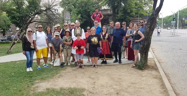 Różnorodna grupa turystów uśmiecha się do zdjęcia w Sofii w Bułgarii, w pobliżu zabytkowego pomnika.