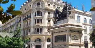 Una hermosa fuente y un edificio ornamentado en una soleada plaza española.