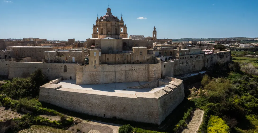 Luftaufnahme einer historischen, befestigten Stadt mit goldenen Steinmauern, Gebäuden und einer großen Kuppelkathedrale un...