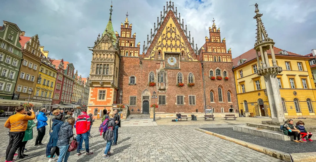 Grupo de turistas admirando el antiguo ayuntamiento en la plaza del mercado de Wrocław.