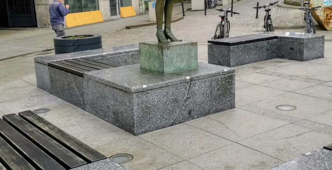 Brązowa statua kobiety trzymającej globus w centrum Wrocławia.