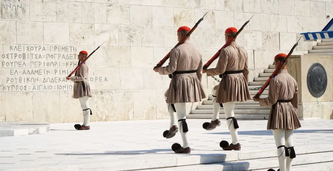 Cuatro guardias Evzones griegos con su uniforme tradicional marchando con rifles durante una ceremonia en Atenas.