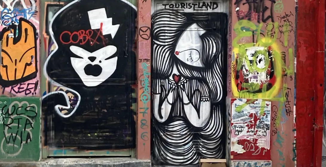 Two urban doors and surrounding walls covered in various street art and graffiti, featuring stylized figures and abstract ...