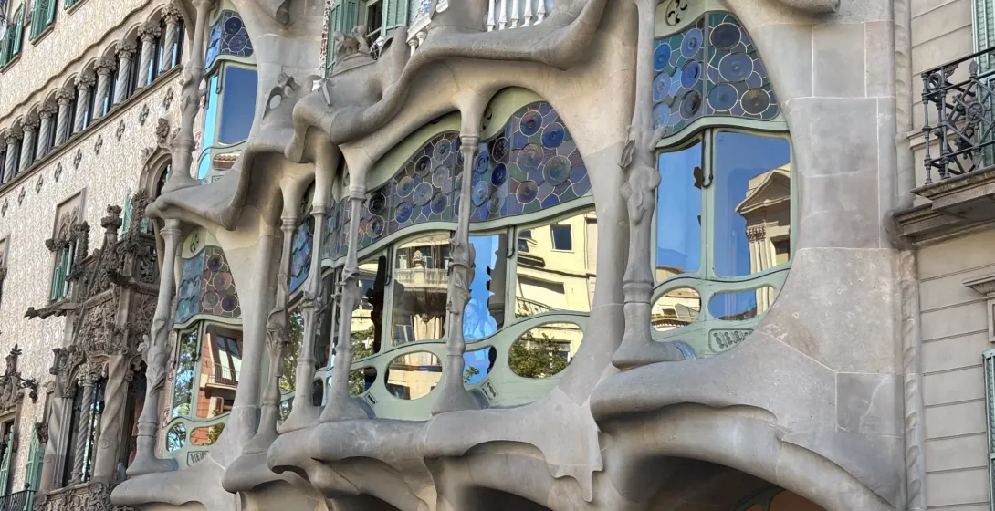 Zbliżenie na fasadę Casa Batlló w Barcelonie, ukazujące unikalne, kościste kolumny i kolorowe witraże Gaudiego.