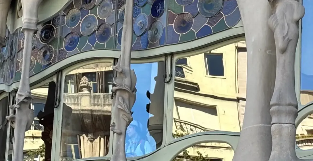 Close-up of Casa Batlló's organic stone balconies and colorful mosaic details under warm light, Barcelona.