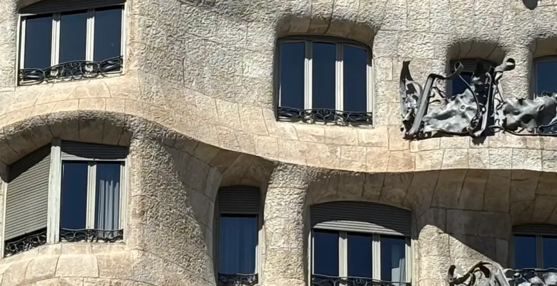 Close-up of Casa Milà (La Pedrera) facade in Barcelona, showing undulating stone, windows, and iron balconies.