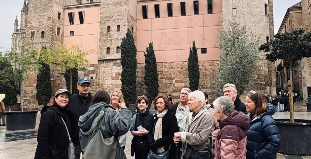 A tour guide speaking to a group of visitors in front of the Cathedral of Barcelona in the Gothic Quarter.