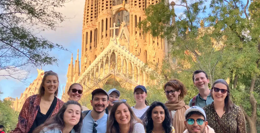 Grupa uśmiechniętych turystów na wycieczce pozuje do zdjęcia przed bazyliką Sagrada Familia Gaudiego w Barcelonie.