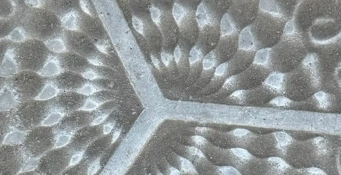 Primer plano de una baldosa hexagonal decorativa gris con patrones orgánicos, escamas y puntos.