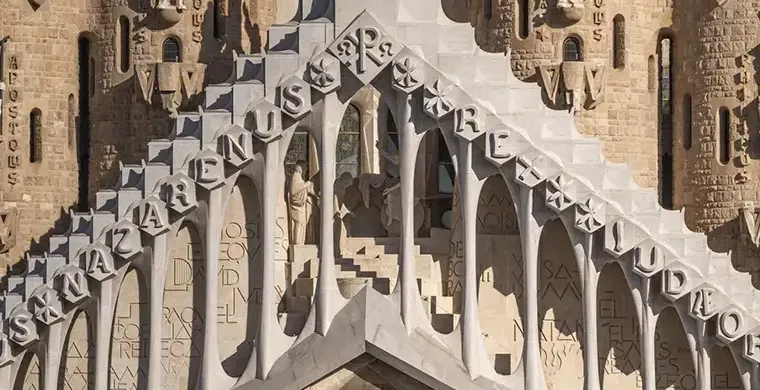 Nahaufnahme der Passionsfassade der Sagrada Família mit geometrischen Formen, vertikalen Türmen und religiösen Skulpturen.