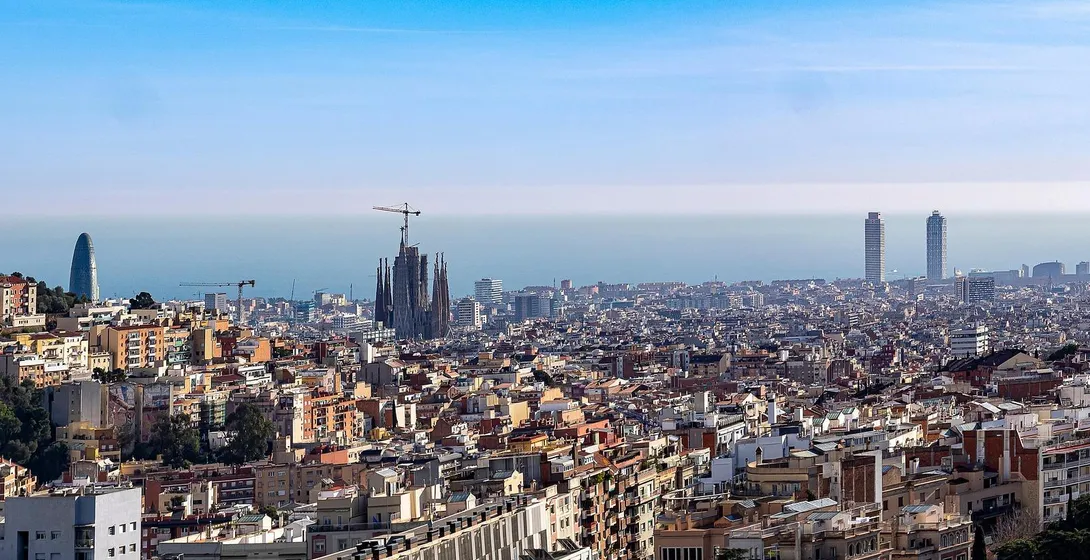 Panoramablick auf Barcelona mit der Sagrada Familia im Bau, dem Agbar Tower und zwei Wolkenkratzern am Meer.