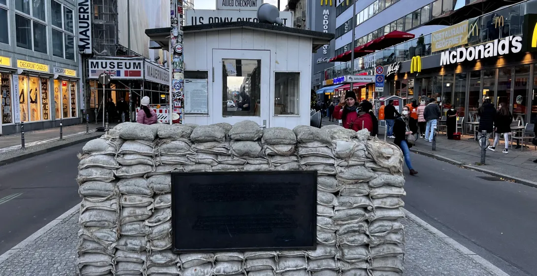 Reconstrucción de la caseta de guardia de Checkpoint Charlie con sacos de arena y placa en una calle adoquinada de Berlín.