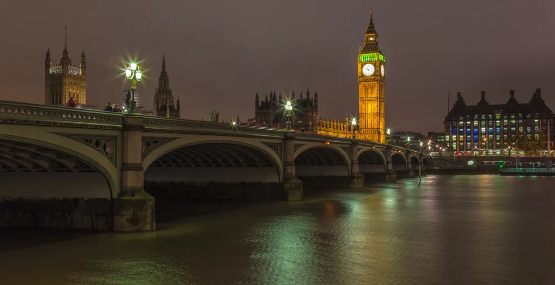 El Big Ben y el Palacio de Westminster iluminados por la noche, vistos sobre el río Támesis con el Puente de Westminster e...