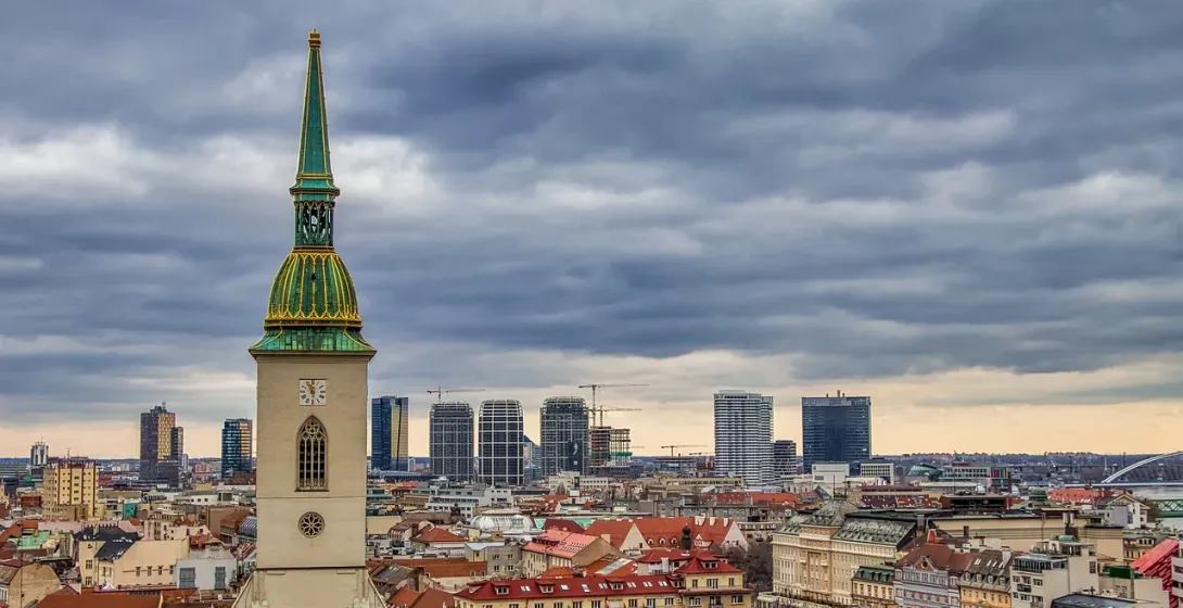 St. Martin's Cathedral tower with green spire and clock face overlooking Bratislava's old town and modern city skyline under