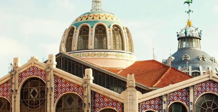 Ozdobne, kafelkowe kopuły i kolorowe dekoracje ceramiczne na fasadzie Mercado Central w Walencji.