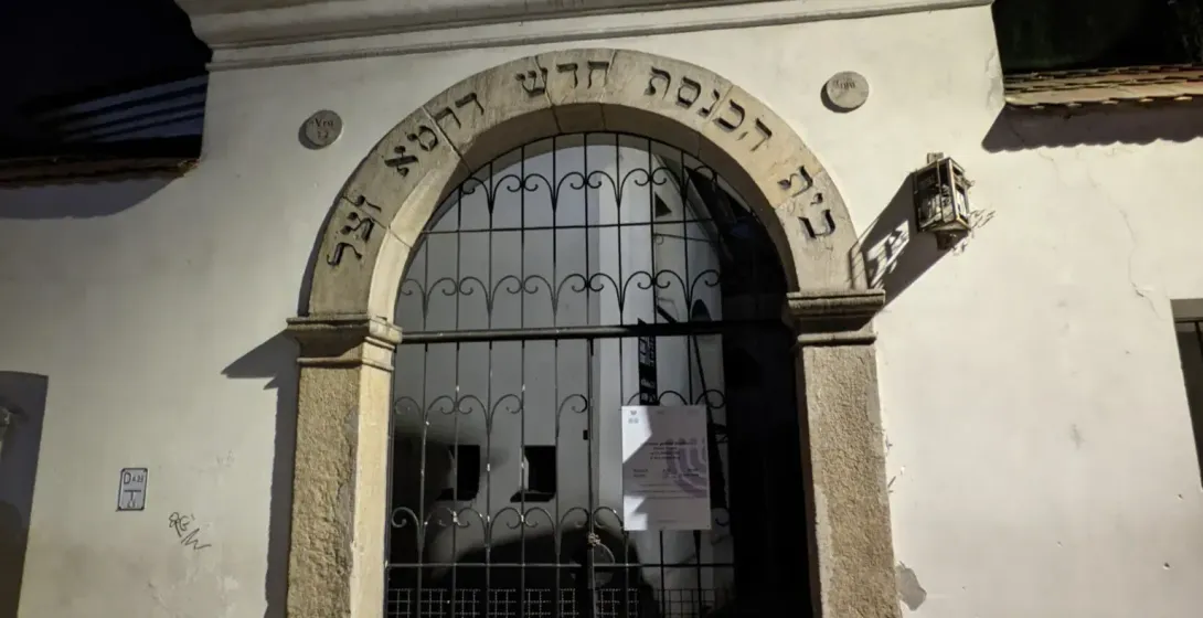 Steinerner Eingang zur Isaak-Synagoge im Krakauer Stadtteil Kazimierz bei Nacht, mit hebräischer Schrift über einem Torbogen.