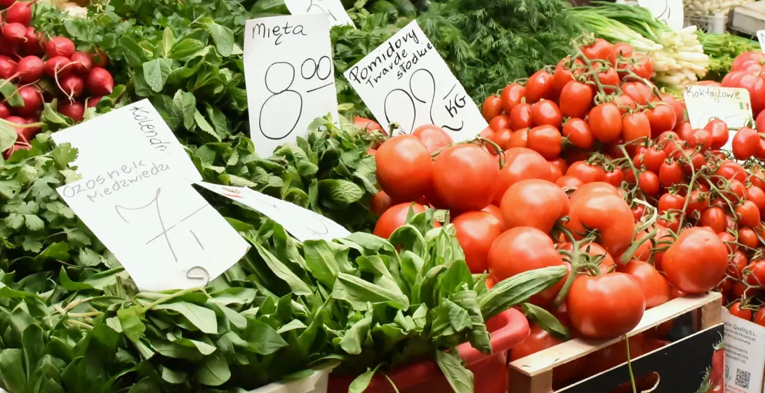 Fresh tomatoes, radishes, and herbs with Polish price tags at a local farmers' market in Krakow.
