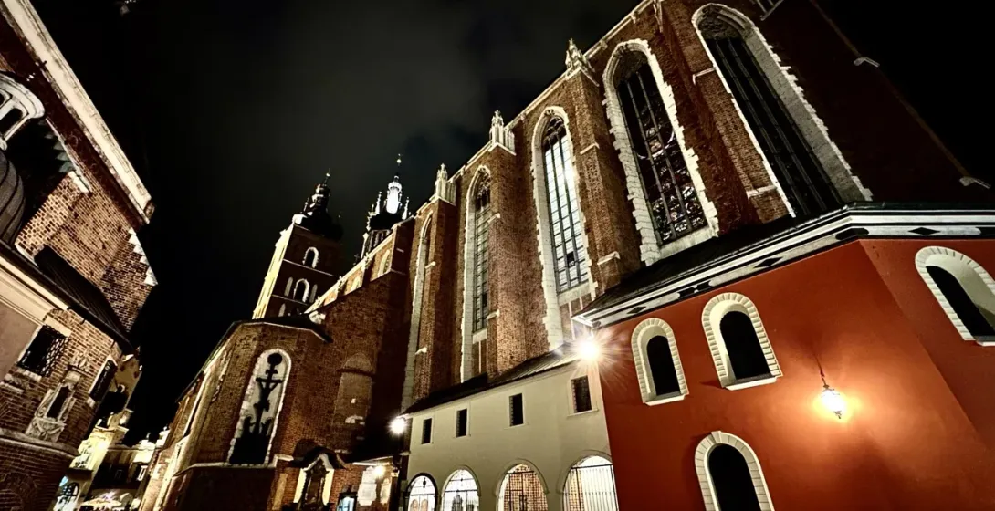 Low-angle view of St. Mary's Basilica in Krakow, illuminated against the dark night sky.