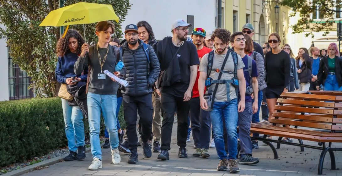 Ein Walkative-Reiseführer mit gelbem Schirm führt eine vielfältige Touristengruppe auf einem Bürgersteig in Krakau.
