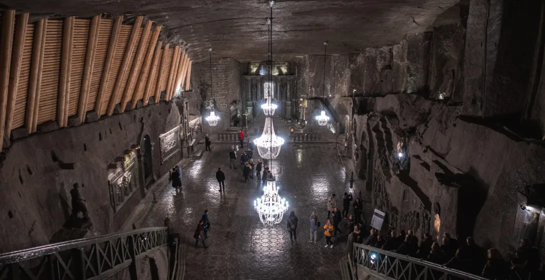View from a balcony into the vast, underground St. Kinga's Chapel in the Wieliczka Salt Mine, lit by salt chandeliers.