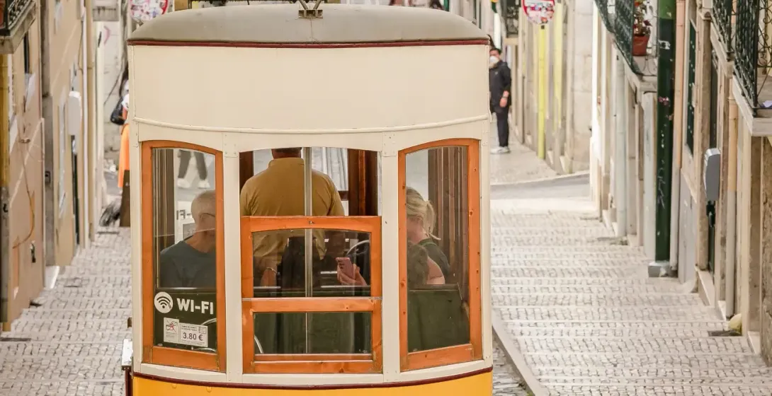 Yellow funicular tram climbing a steep cobbled street lined with historic buildings in Lisbon.