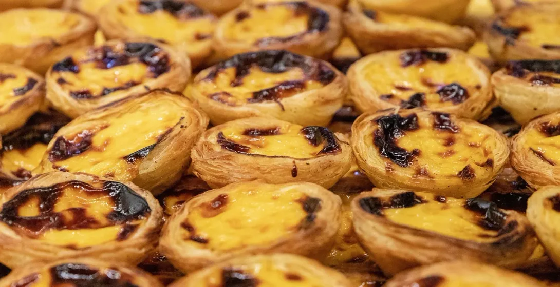 Eine Nahaufnahme von vielen Pastéis de Nata, portugiesischen Puddingtörtchen mit einer dunklen, karamellisierten Oberseite.