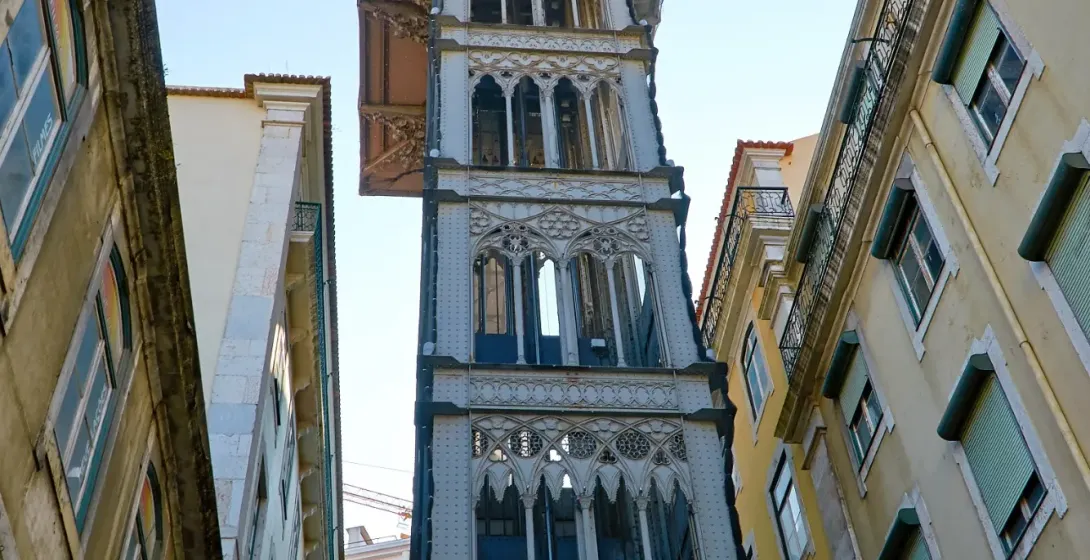 The neo-Gothic Santa Justa Lift, an iron elevator in Lisbon, viewed from street level between buildings.