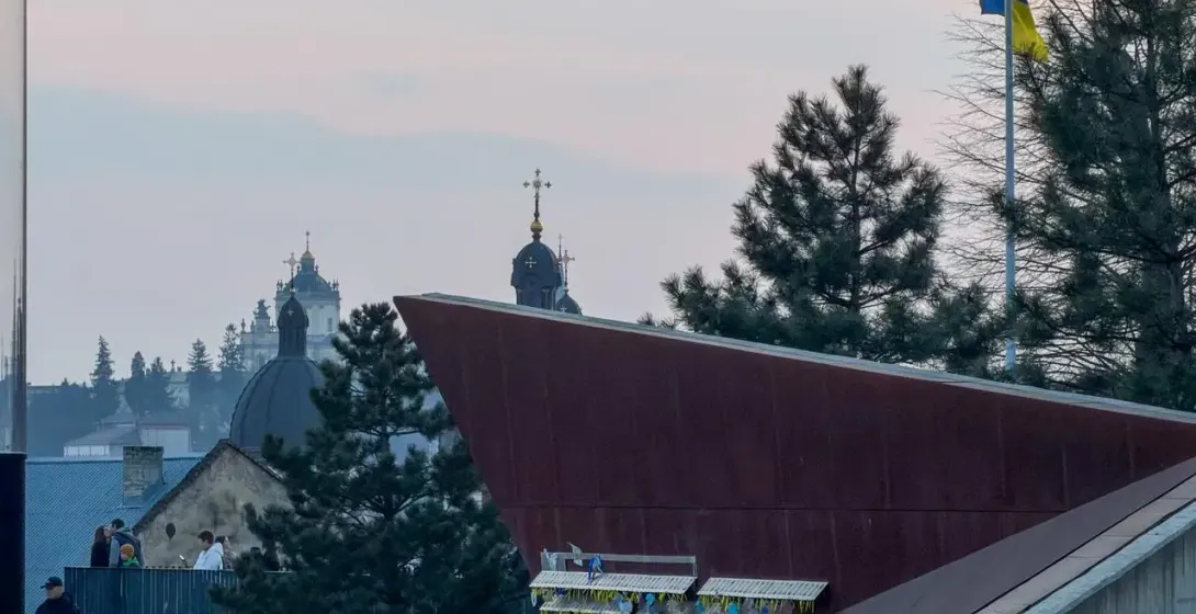 Lemberger Skyline mit Kirchendomen, einem modernen Gebäude, Menschen auf einem Weg und einer ukrainischen Flagge bei Dämme...