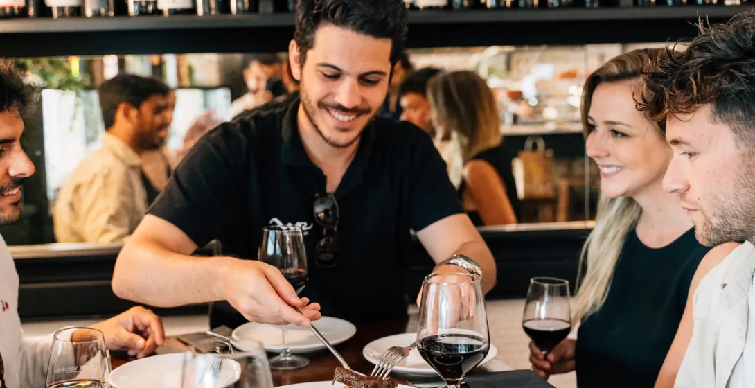 Un grupo de amigos comparte comida y vino tinto en la mesa de un bar de tapas de Madrid.