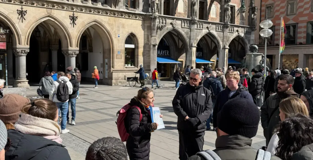 A tour guide talks to a group of tourists in Marienplatz square, in front of Munich's New Town Hall.