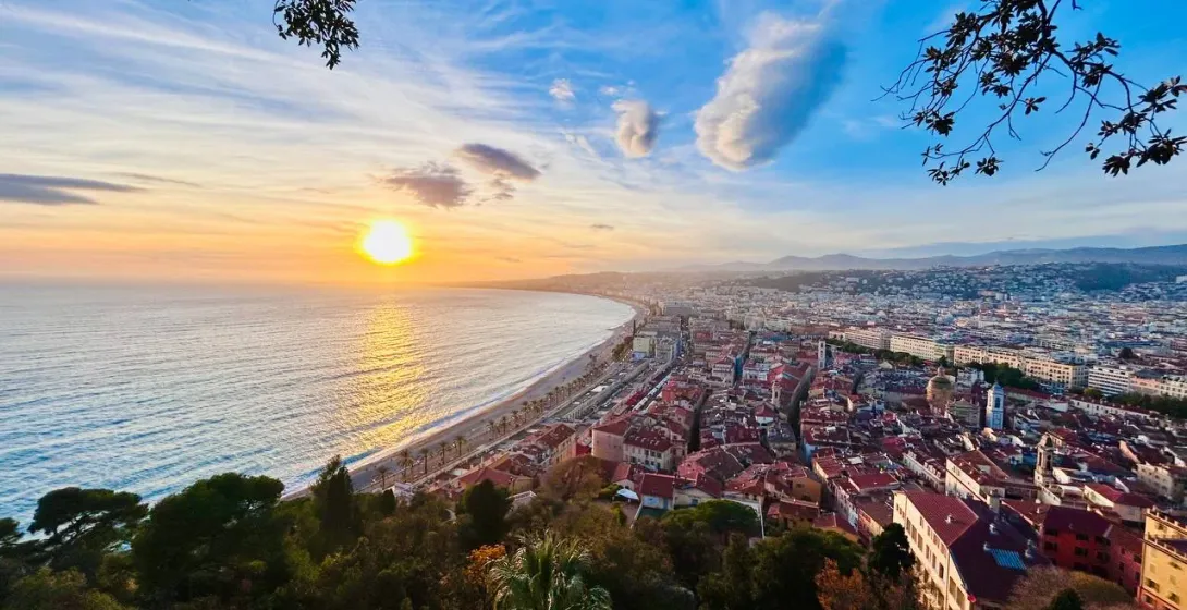 Aerial view of Nice coastline at sunset, with the Promenade des Anglais, Mediterranean Sea, and city buildings under an or...
