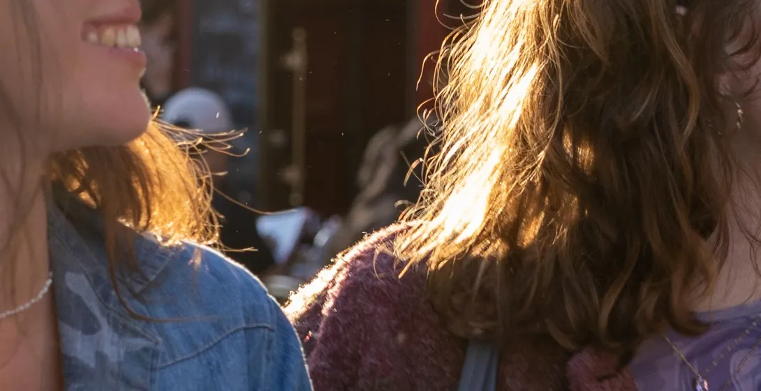 Dos personas con cabello iluminado por el sol frente al restaurante La Mère Catherine en Montmartre, París.