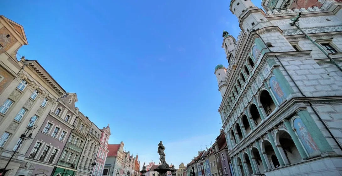 Panoramablick auf den Alten Markt in Posen mit farbenfrohen Bürgerhäusern, einem großen Brunnen und dem verzierten Renaiss...