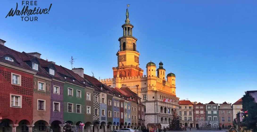 Altes Rathaus von Posen mit hohem Uhrturm, umgeben von farbenfrohen historischen Kaufmannshäusern unter klarem Himmel.