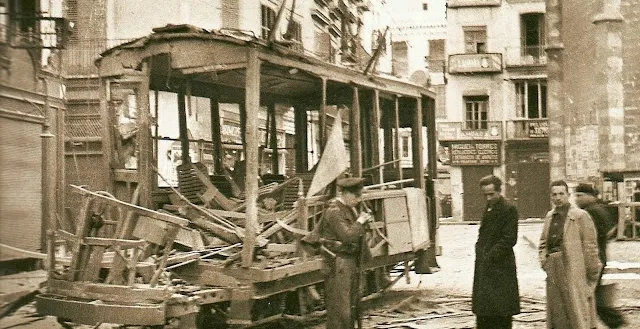 A destroyed tram on a street in Valencia during the Spanish Civil War. Sepia-toned photograph.