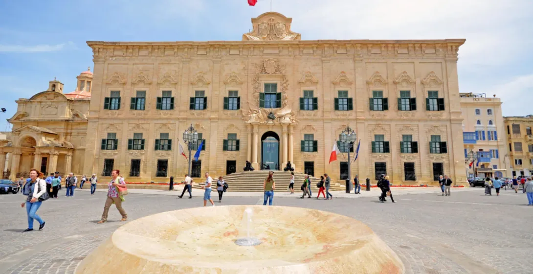 La Auberge de Castille, un edificio barroco adornado con contraventanas verdes y la bandera maltesa, en la Plaza de Castille