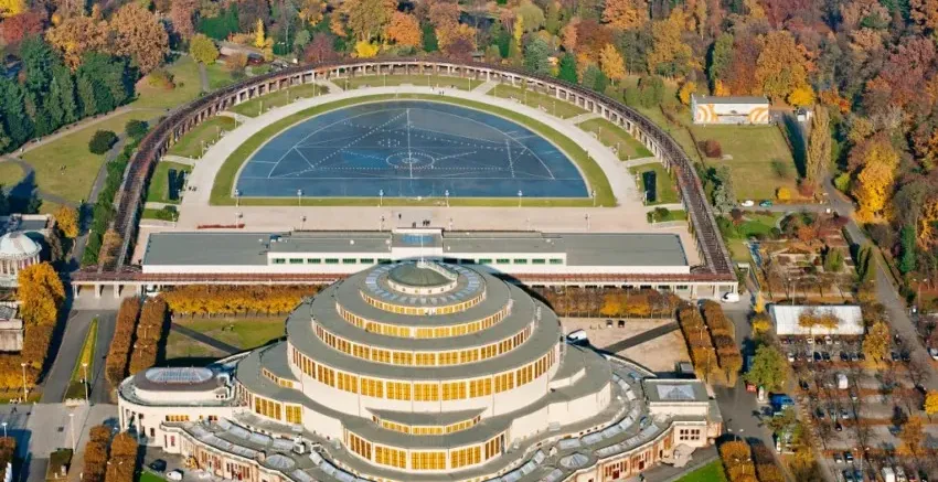 Aerial view of Centennial Hall in Wroclaw with its circular tiered roof, surrounded by the semicircular Pergola and autumn...