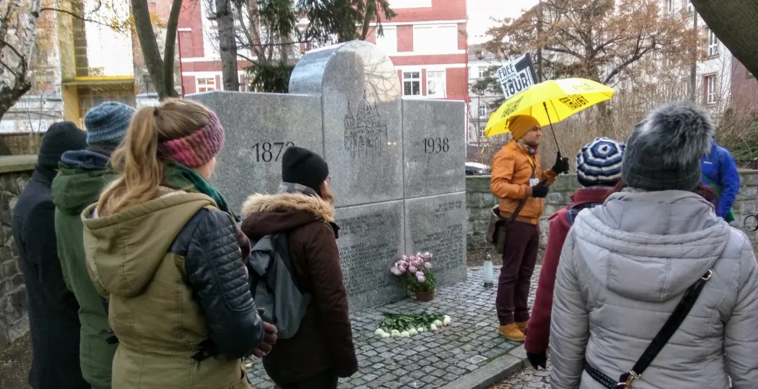 A guided walking tour group in Wrocław, Poland, listens attentively to their guide at a historical monument.