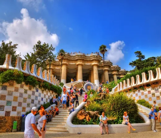 Turyści zwiedzają pełną życia mozaikową architekturę Parku Güell w Barcelonie.