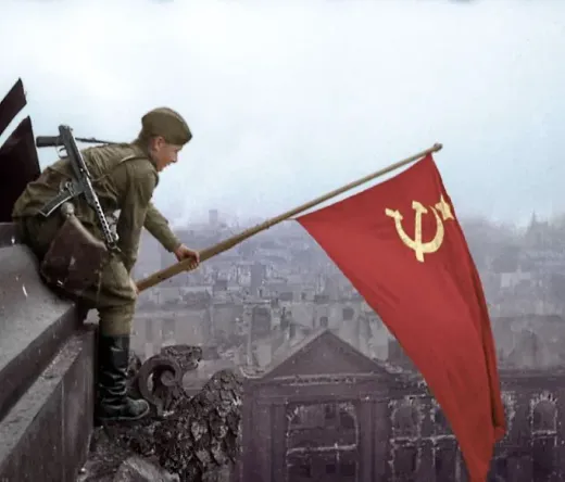 Radziecki żołnierz podnosi flagę w zniszczonym Berlinie.