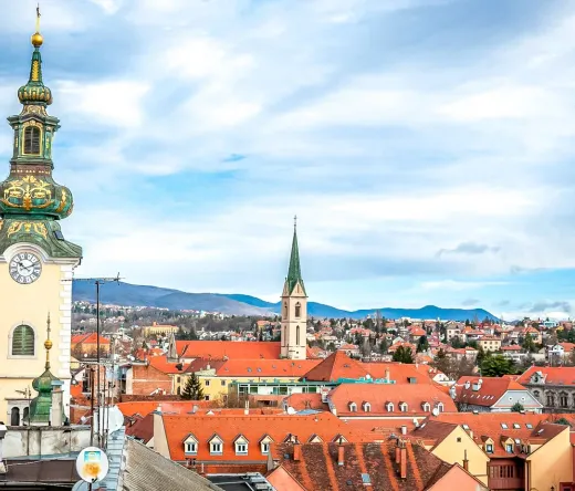 Vista panorámica de Maribor, Eslovenia, con una destacada torre del reloj y tejados de terracota.