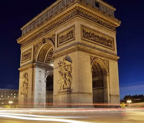 Łuk Triumfalny w Paryżu nocą, pięknie oświetlony.