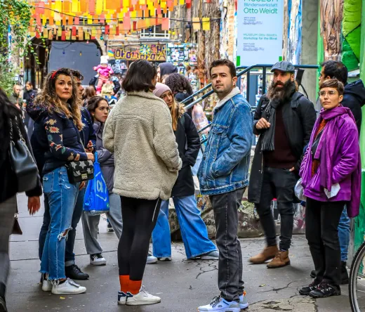 Tourists exploring a vibrant Berlin street art alley.