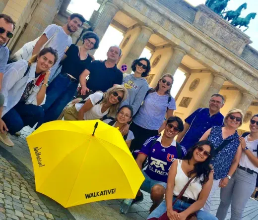 Turistas felices en un tour WALKATIVE! frente a la Puerta de Brandeburgo en Berlín.