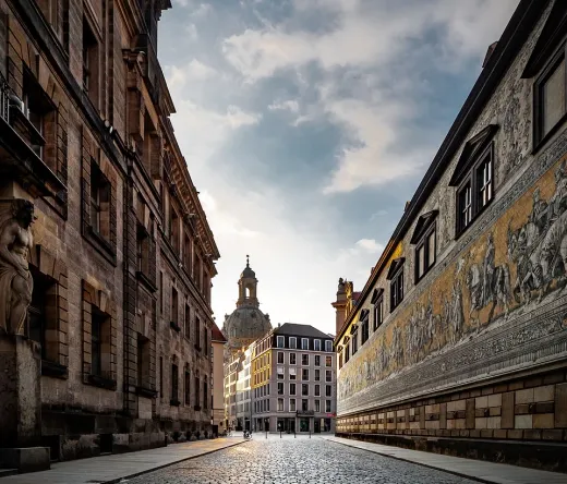 Calle empedrada en Dresde, Alemania, con edificios históricos y un fresco.