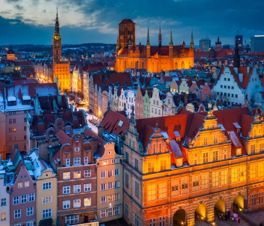Enchanting twilight view of Gdansk's Old Town, Poland, with snow-dusted rooftops and illuminated historic buildings.