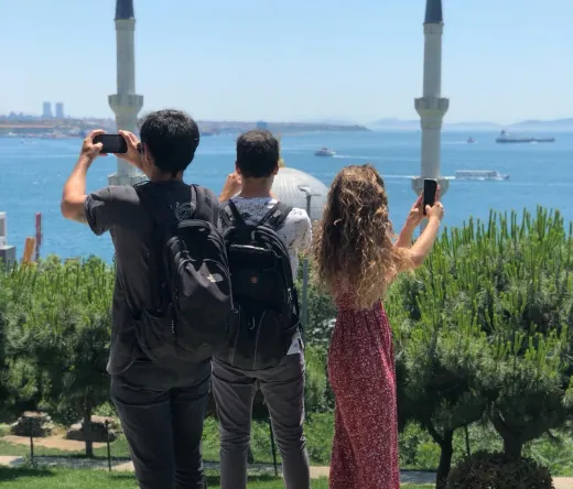 Tourists taking photos of a beautiful mosque and the Bosphorus in Istanbul.