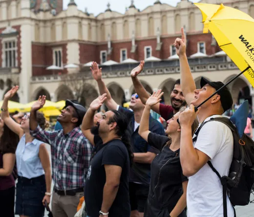 A Walkative! Free Tour guide leads a group of tourists in Krakow's Main Market Square.